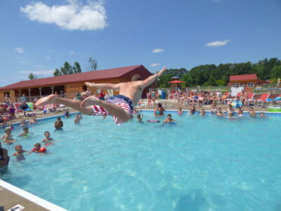 Swimming Pool Fun at Jellystone Park™ Family enjoying the swimming pool at Jellystone Park™ with guests jumping and playing in the water