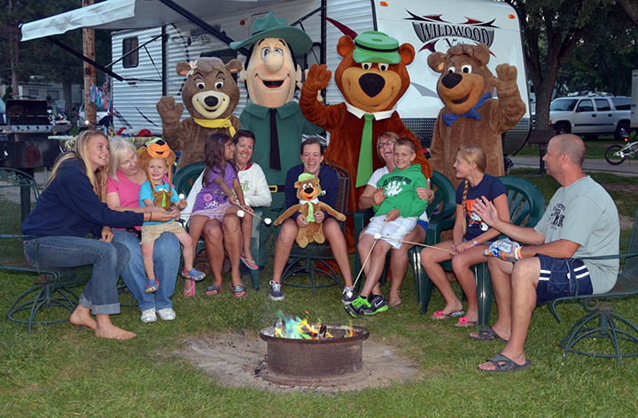 Families enjoying campfire time with costumed characters at Jellystone Park™