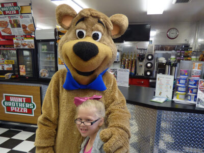 Boo Boo Bear greeting guests at the Cartoon Café counter at Jellystone Park™ South Haven